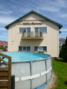 a building with a swimming pool in front of a house at Willa Murena in Mielno