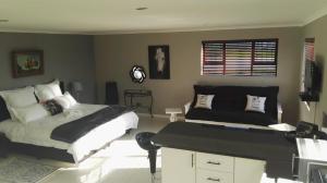 a bedroom with a bed and a couch at Bergsig Selfcatering in Gordonʼs Bay