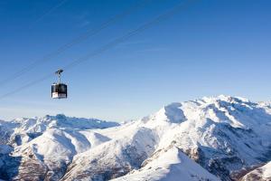 un remonte que vuela sobre una montaña cubierta de nieve en Vacancéole - Résidence Alpina Lodge, en Les Deux Alpes