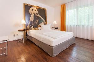 1 dormitorio con 1 cama grande y una pintura en la pared en Hotel der Lennhof, en Dortmund