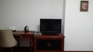 a tv sitting on a wooden stand with a desk at Huizhan Ge Aparthotel in Shenzhen