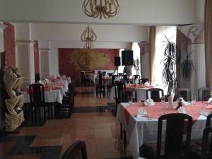 a restaurant with tables and chairs with red and white tablecloths at Paradise Hotel in Madzharovo