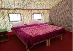 a bedroom with a bed with a purple comforter at Shyok Camp - Nubra in Nubra