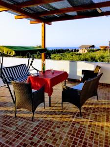una mesa y sillas en un patio con vistas al océano en Agriturismo Aiolia - Panorama Eolie, en Mongiove