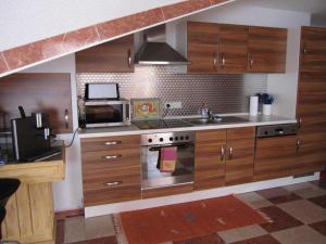 a kitchen with wooden cabinets and a stove and a microwave at Ferienwohnung Kunst in Mahlberg