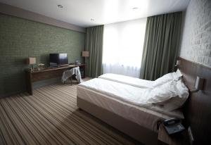 ノヴォロシースクにあるCapital Hotelのベッド、デスク、テレビが備わるホテルルームです。