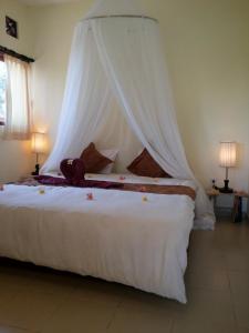 1 dormitorio con 1 cama blanca grande con dosel en Fishermen's Guesthouse, en Amed