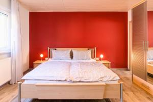 a bedroom with a large bed with a red wall at Domizil Nunn in Escherndorf