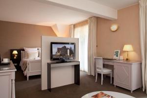 a hotel room with a television and a bed at Logis Hotel Le Parc & Spa in Saint-Hippolyte