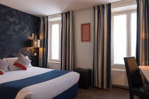 ein Hotelzimmer mit einem Bett und zwei Fenstern in der Unterkunft Hotel France Albion in Paris