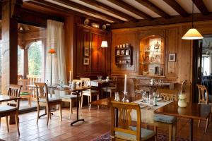 ein Restaurant mit Holzwänden, Tischen und Stühlen in der Unterkunft Logis Hotel Le Parc & Spa in Saint-Hippolyte