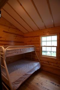 łóżko piętrowe w drewnianym domku z oknem w obiekcie Yukon Trails Camping Resort w mieście Lyndon Station