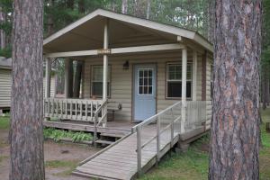 mały domek z werandą w lesie w obiekcie Yukon Trails Camping Resort w mieście Lyndon Station
