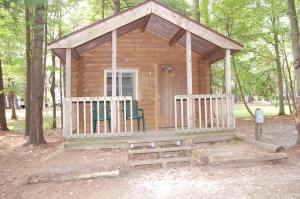 a wooden cabin in the woods with two chairs at St. Clair Camping Resort in Marysville
