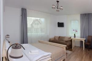 a white bedroom with a bed and a couch at Pensiunea Karola in Păltiniş