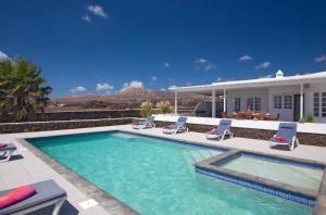 a swimming pool with chairs and a house at Villa Las Palmitas in Puerto Calero