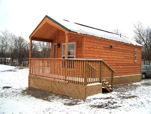 a wooden cabin with a porch in the snow at Wilmington Camping Resort in Wilmington