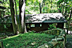 a stone fence in front of a house in the woods at Bear Cave Camping Resort in Buchanan