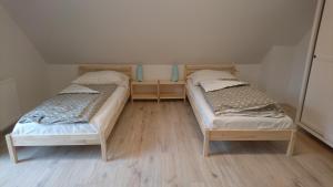 two beds in a small room with wooden floors at Kaszubówka 29 in Załakowo