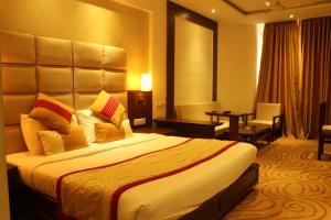 a hotel room with a large bed and a desk at Hotel Gwalior Regency in Gwalior