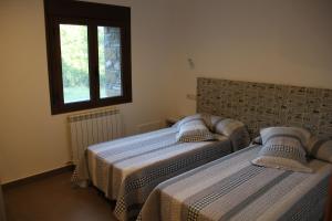 two beds in a bedroom with a window at Casa sierra ferrera in Samper