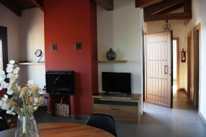 a living room with a tv and a table and a door at Casa sierra ferrera in Samper
