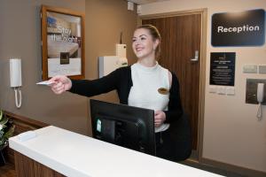 a woman standing at a counter holding a piece of paper at Chain Runner, Livingston by Marston's Inns in Livingston