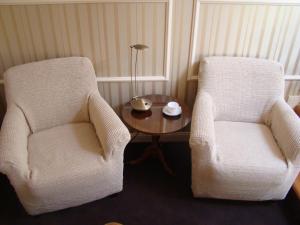2 sillas blancas y una mesa en una habitación en Ricardpol Noclegi, en Tarnów