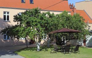 ヘウムノにあるApartamenty w sercu Chełmnaの木の下の傘下のテーブルと椅子