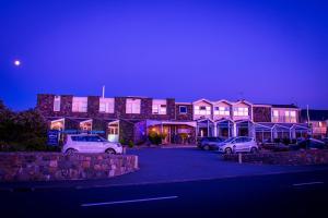 a building with cars parked in a parking lot at night at Driftwood Inn in St. Saviour Guernsey
