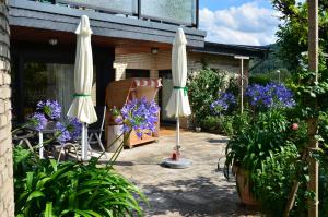 eine Terrasse mit zwei weißen Sonnenschirmen und lila Blumen in der Unterkunft Fewo Amber in Heimbach + 4 Fotos