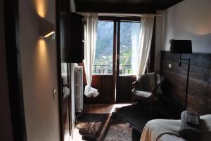 1 dormitorio con ventana, 1 cama y 1 silla en Hotell Millefiori- Alpine Event Lodge en Valtournenche