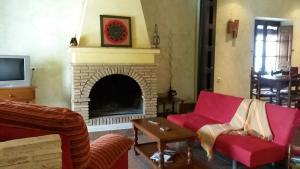 a living room with a fireplace and red furniture at Casa Rural del Rio in La Nava