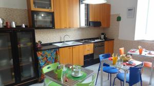 una cocina con armarios de madera, mesa y sillas en CASA Melone Giallo, en Paceco