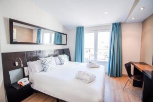 um quarto com uma grande cama branca com cortinas azuis em Petit Palace Plaza de la Reina em Valência