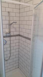 a bathroom with a shower with white tiles at The Wheatsheaf Inn in Ingleton 