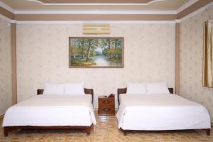 2 Betten in einem Zimmer mit Wandgemälde in der Unterkunft Phu Qui Hotel in Soc Trang