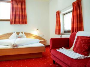 una camera d'albergo con un letto e un divano rosso di Pension Apartment Erna a Resia