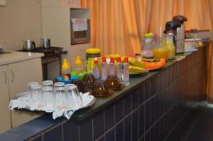 a counter in a kitchen with bottles and plates of food at Hotel Alvorada I in Sete Lagoas
