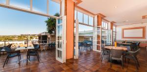 Un comedor con mesas y sillas y grandes ventanales. en Globales Samoa, en Calas de Mallorca