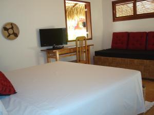 a bedroom with a white bed and a television at Torre de Chocolate Pousada in Barra Grande