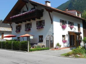 a white building with flowers on the windows at Alpenperle in Bichlbach