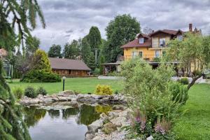 a house with a pond in front of a yard at Penzion Fantázia Michalová in Michalová