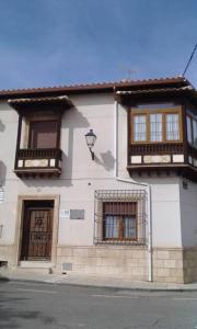 a white building with two windows and a door at El Balcón de la Mancha in Tembleque