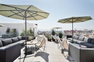 eine Dachterrasse mit Tischen, Stühlen und Sonnenschirmen in der Unterkunft Yurbban Passage Hotel & Spa in Barcelona