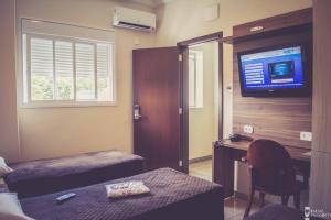 1 dormitorio con escritorio y TV en la pared en Jardim Hotel en São Bernardo do Campo