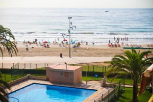 ラ・ピネーダにあるPINEDA 4 Planet Costa Doradaのスイミングプールと人々が集まるビーチの景色を望めます。