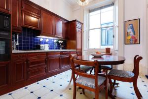 - une cuisine avec des placards en bois, une table et des chaises dans l'établissement Veeve - Queen's Gardens Flat, à Londres