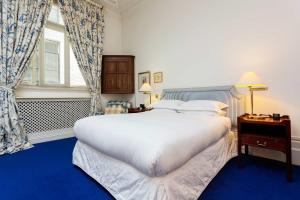 una camera da letto con un grande letto bianco e una finestra di Veeve - Queen's Gardens Flat a Londra