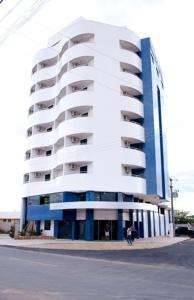 a tall white building with people standing in front of it at Rapport Hotel in Juazeiro